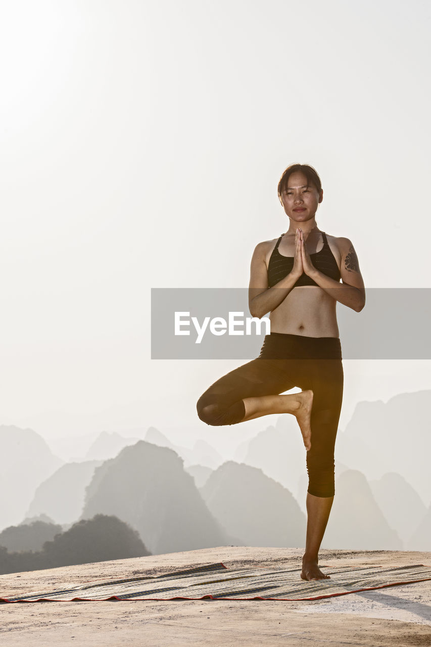 Beautiful woman practising yoga above the kast mountains of yangshuo