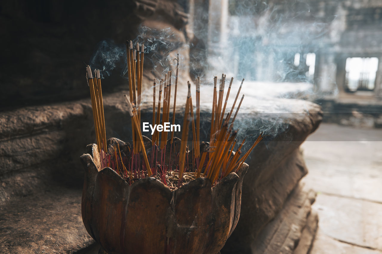Incense sticks burning with smoke in ancient temple in cambodia.