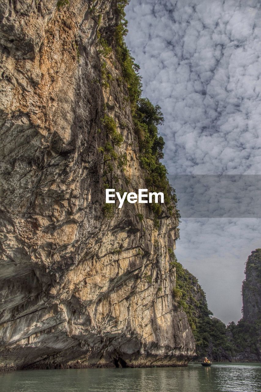 Steep cliff against cloudy sky