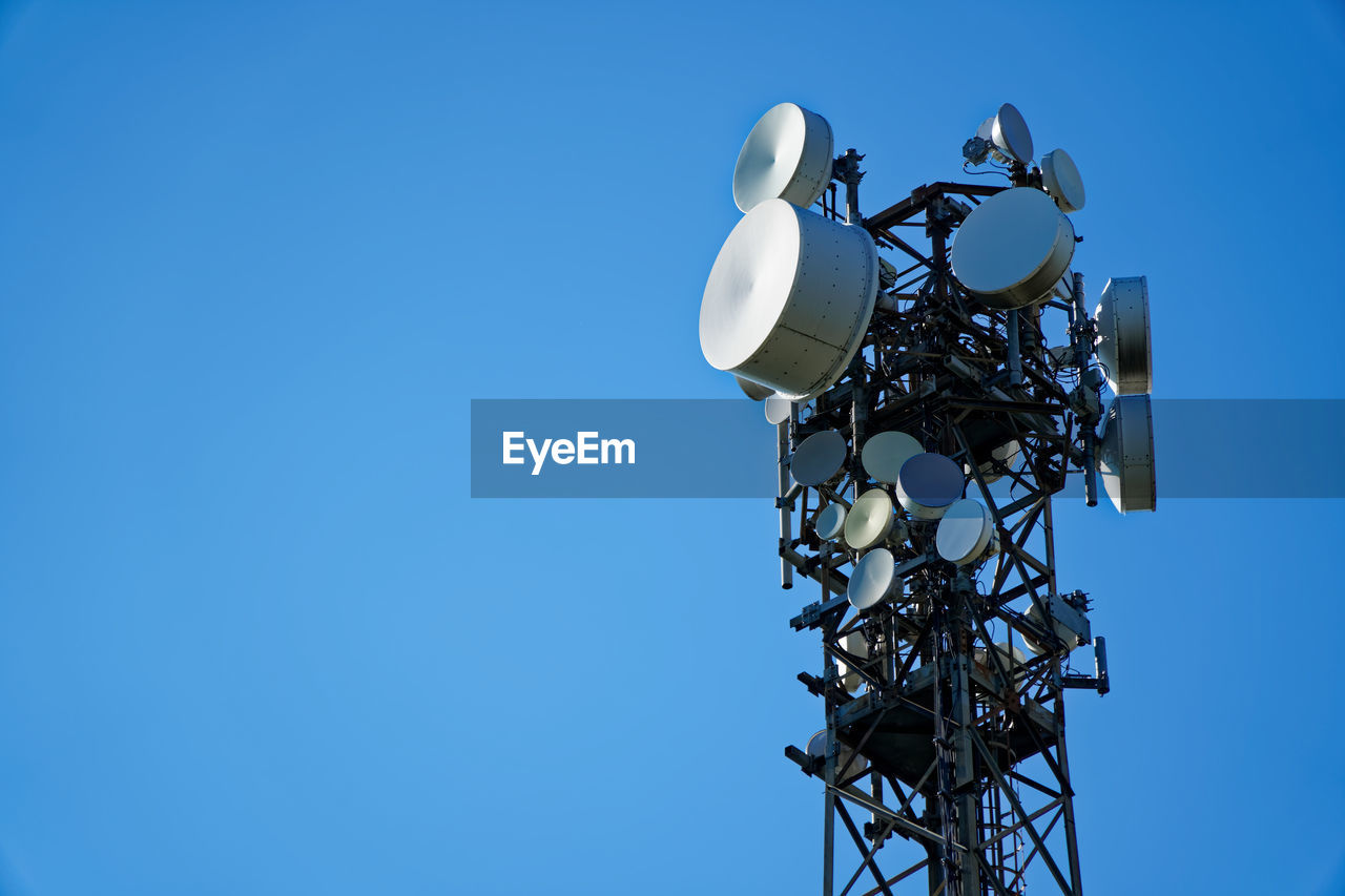 Low angle view of communications tower against clear blue sky