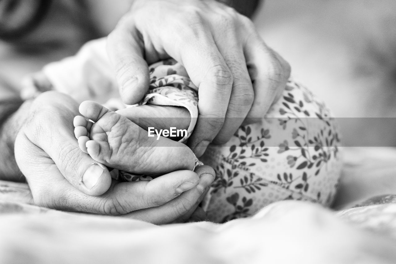 Cropped image of mother holding baby foot