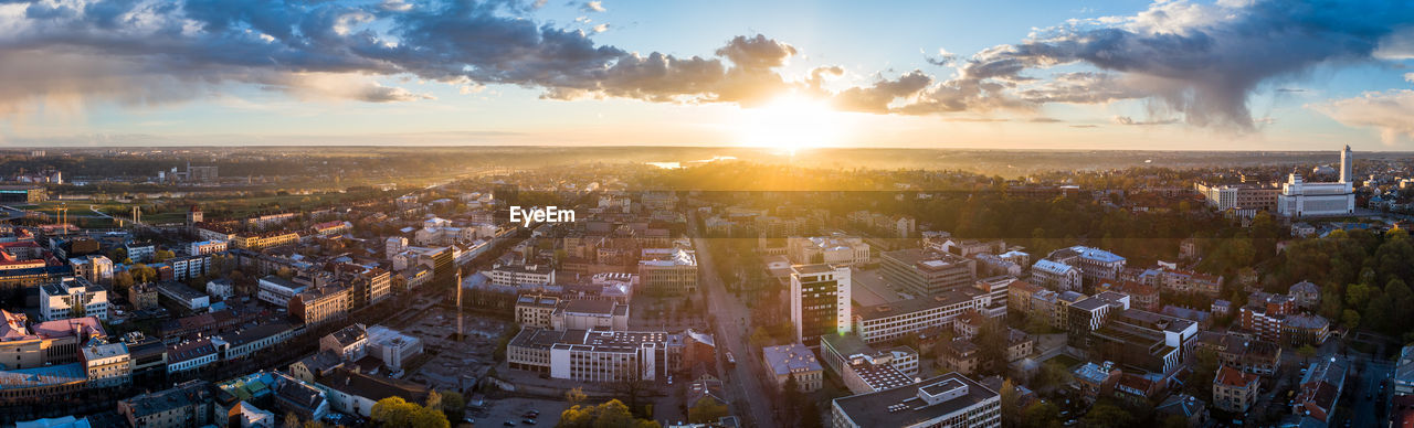 HIGH ANGLE VIEW OF ILLUMINATED CITYSCAPE AGAINST SKY DURING SUNSET