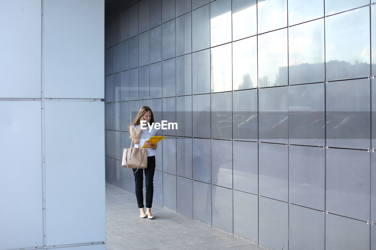 Woman standing against wall of building