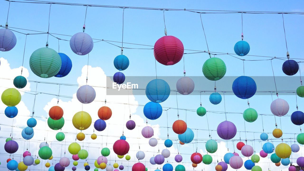 Low angle view of lanterns hanging against blue sky