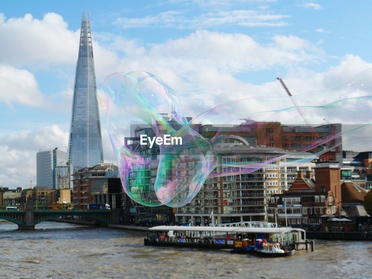 Close-up of bubble against river and buildings in city