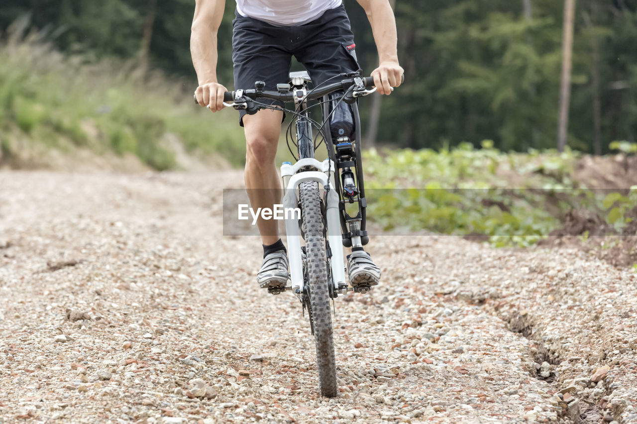 Low section of man riding bicycle on footpath