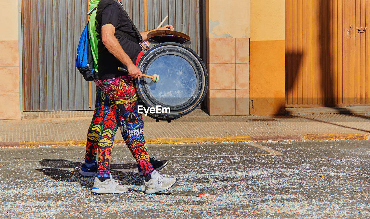 Popular festivals man playing bass drum in multicolored suit. popular festivities