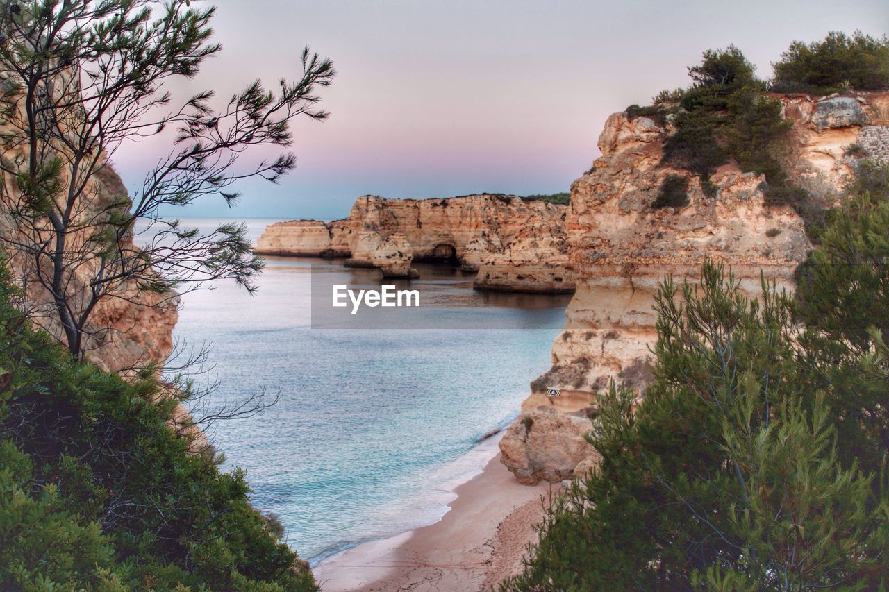 Rock formations in sea at praia da marinha during sunset