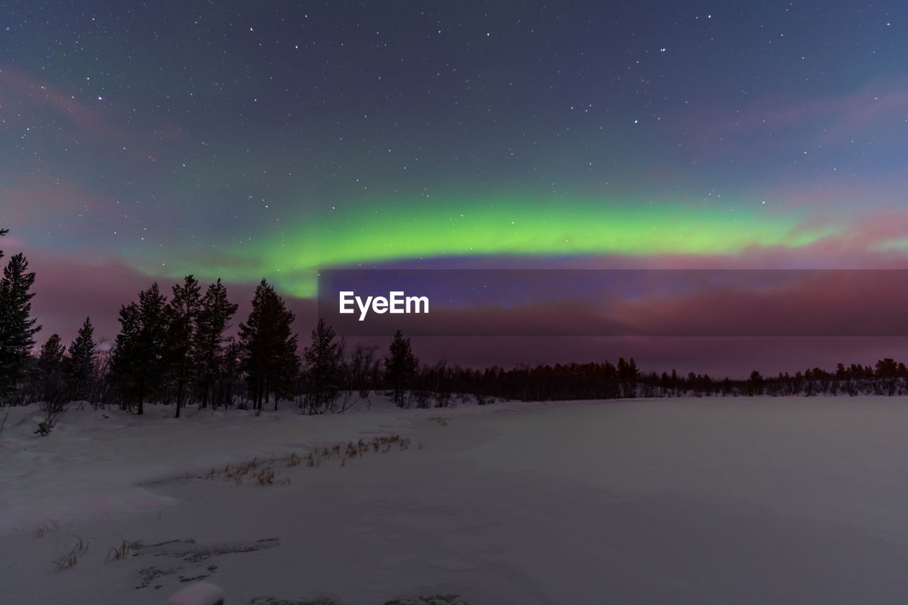 Scenic view of snowcapped landscape against sky at night with aurora borealis 