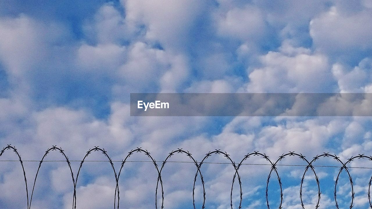 Low angle view of razor wire against sky