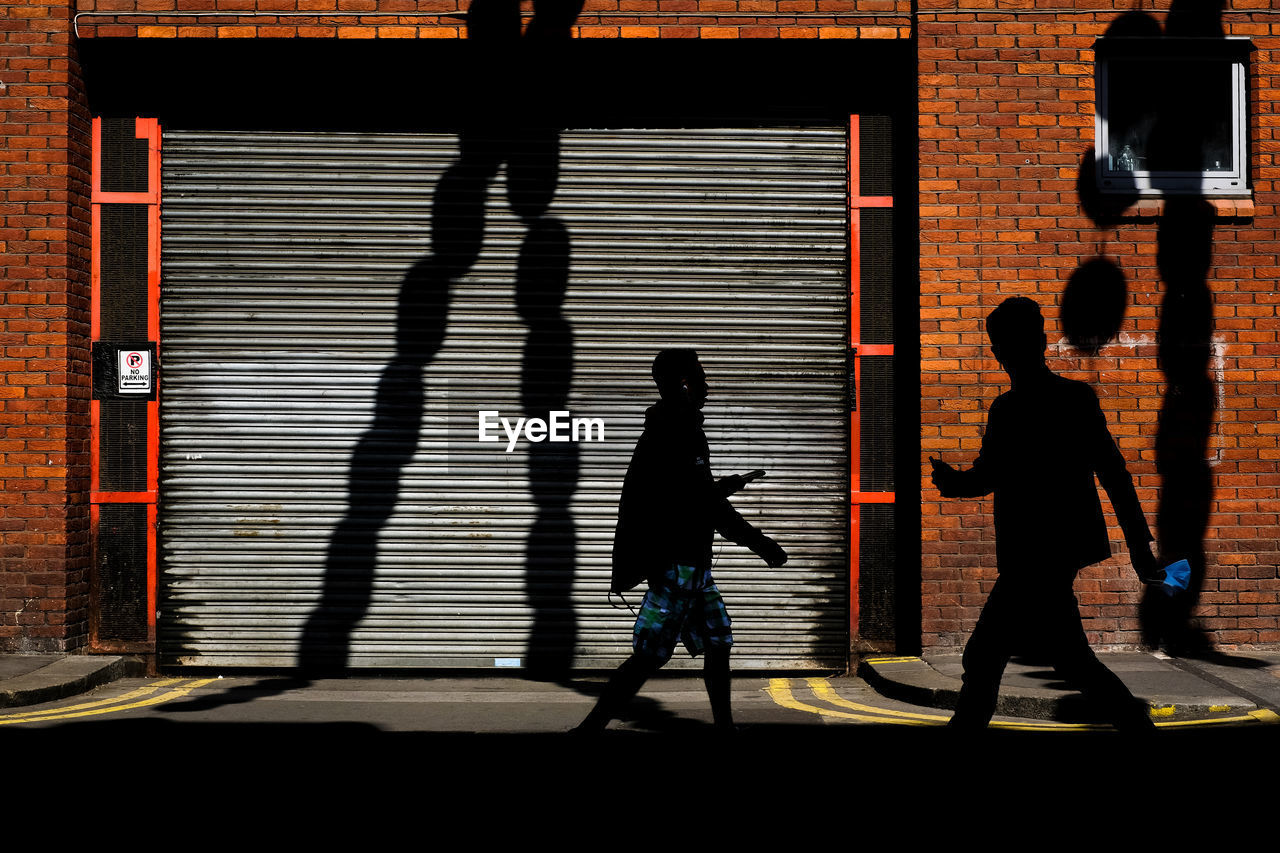 Silhouette people walking in front of building