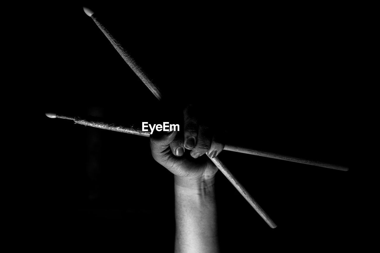 Close-up of hand holding metal against black background