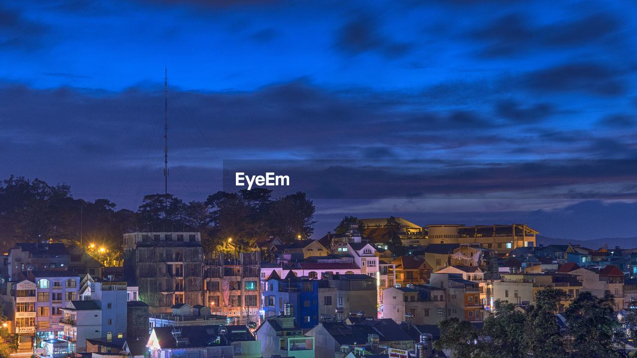 Illuminated buildings against blue sky in city at night