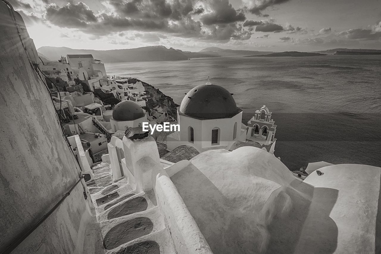 Scenic view of residential houses at santorini by sea against sky