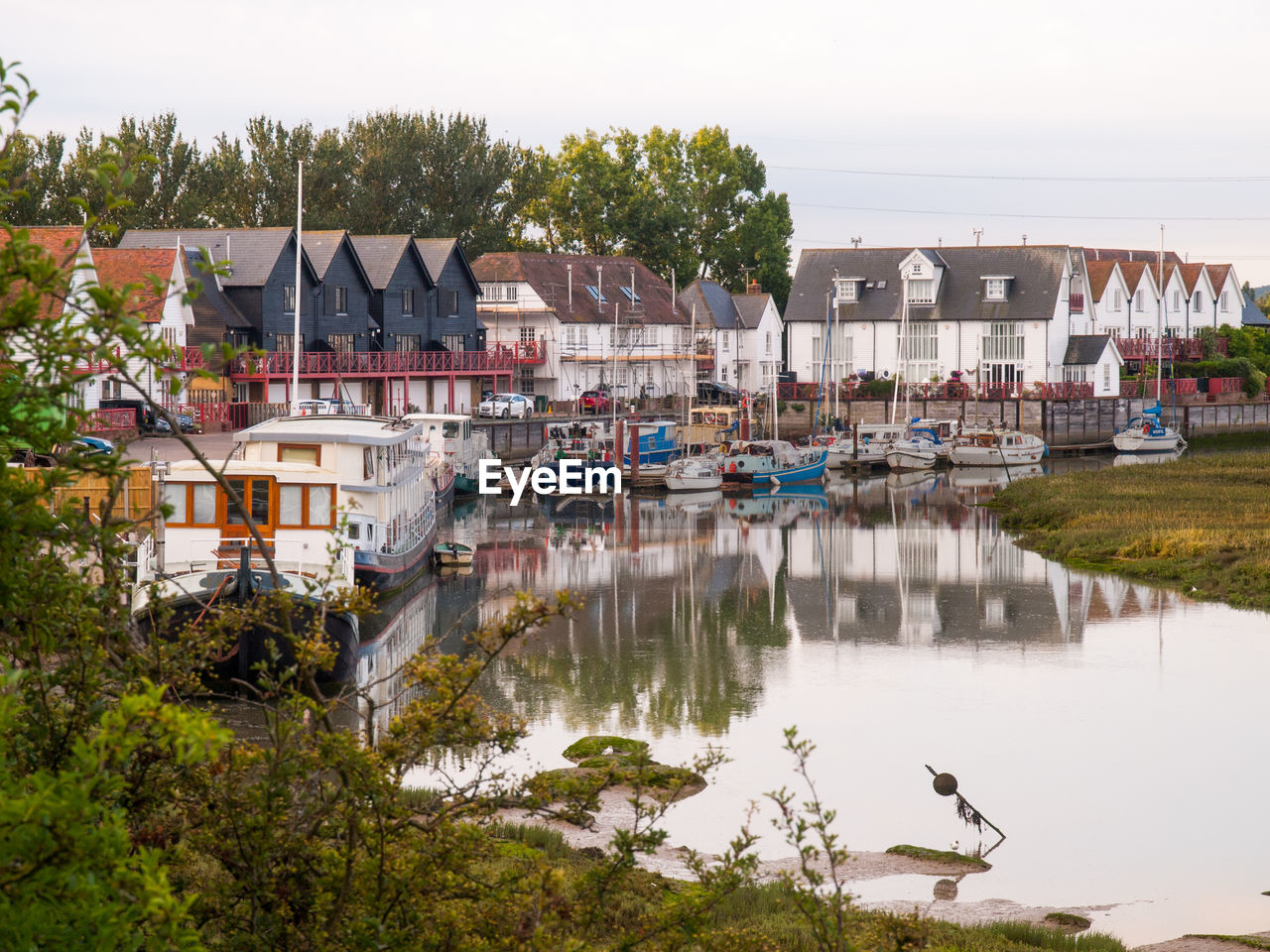 BOATS MOORED BY LAKE AGAINST BUILDINGS