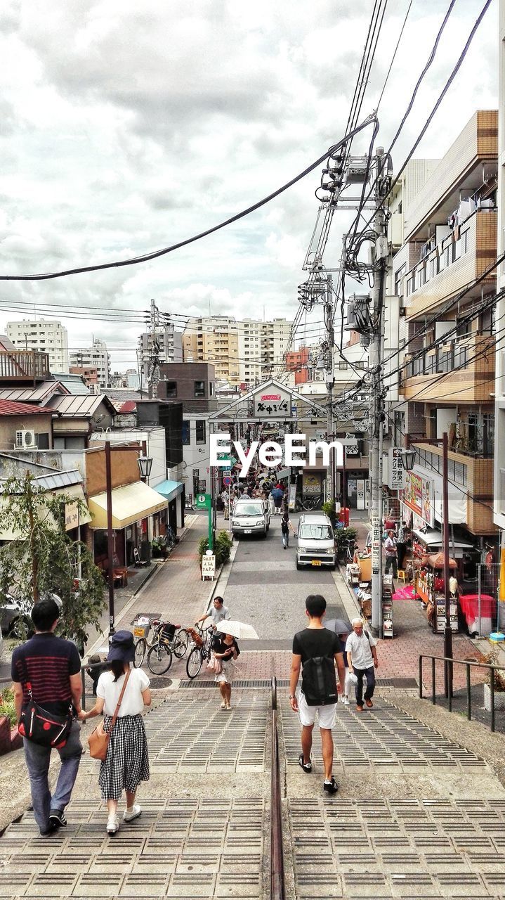 PEOPLE WALKING ON STREET AGAINST BUILDINGS