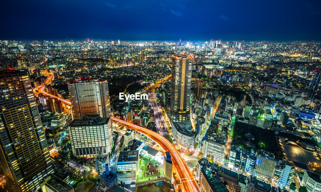 Aerial view of highway amidst buildings in city at night