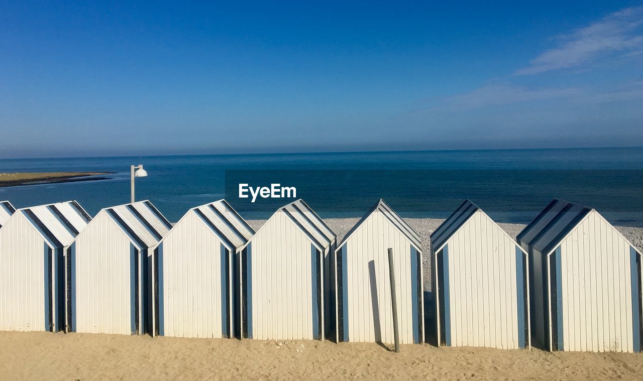 Beach huts in row against blue sky 