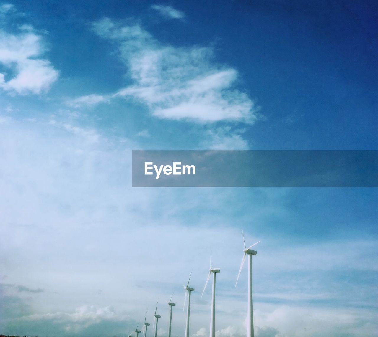 Row of wind turbines against sky