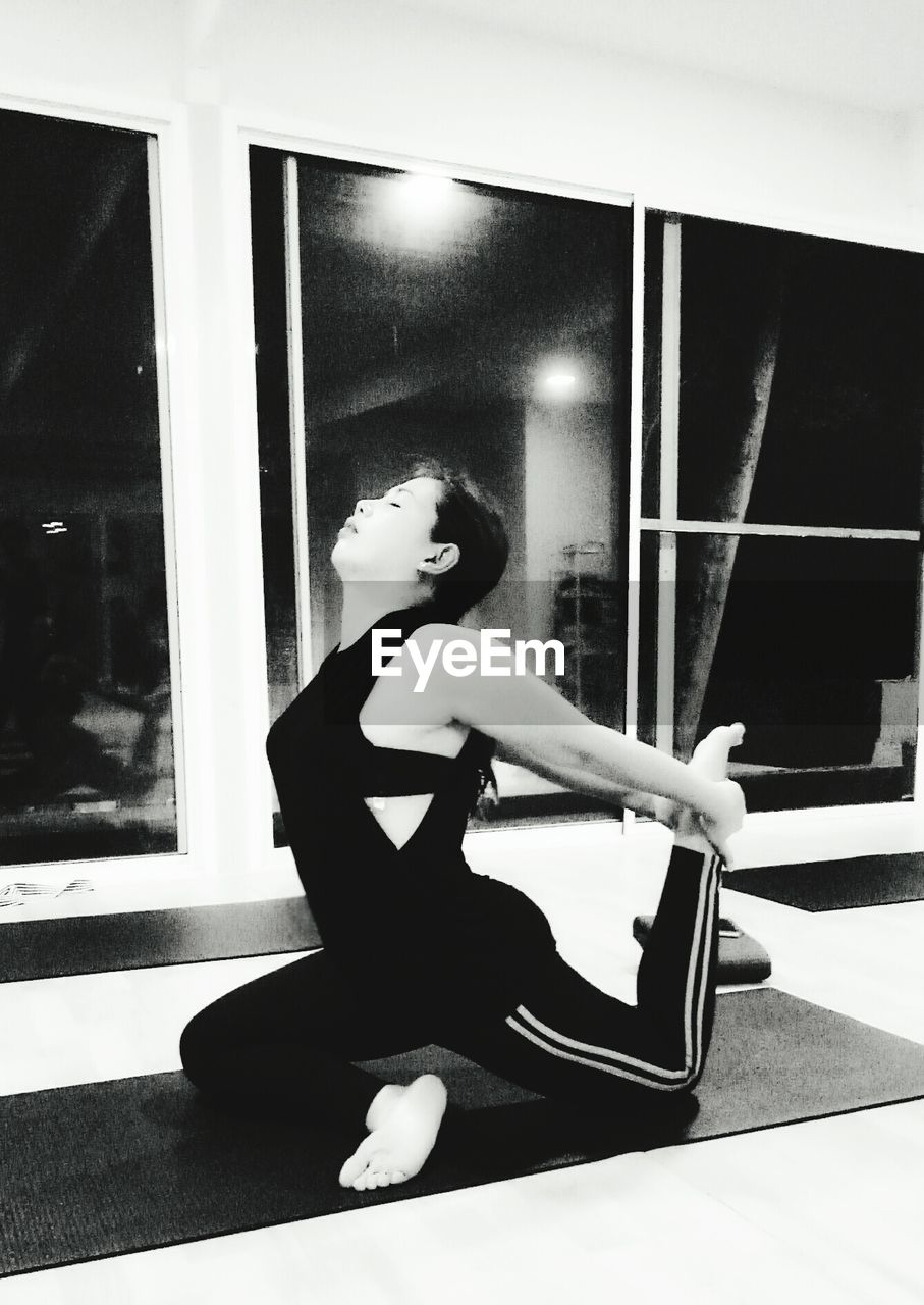 SIDE VIEW OF YOUNG WOMAN SITTING ON TABLE