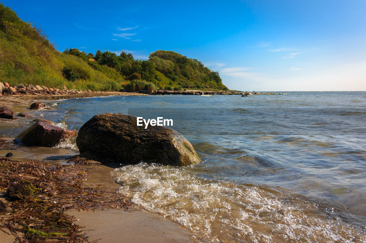 SCENIC VIEW OF ROCKY BEACH AGAINST SKY