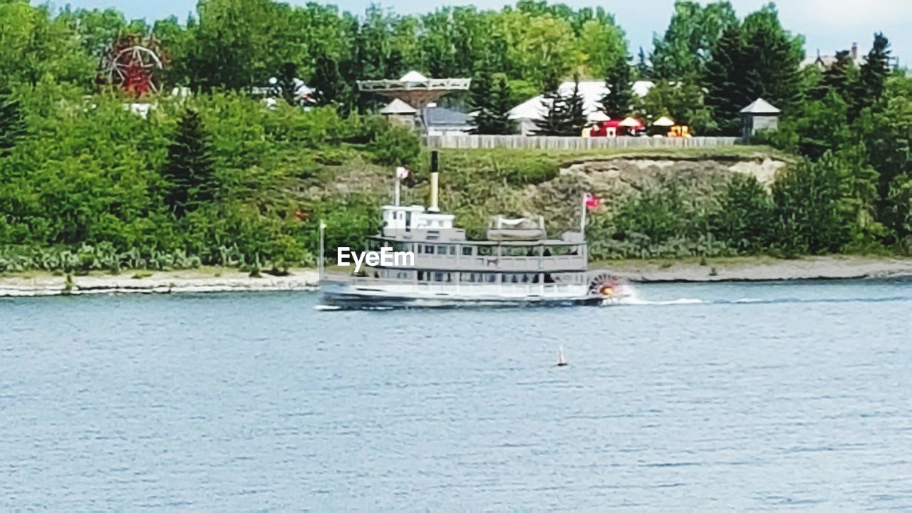 BOATS SAILING ON RIVER BY TREES