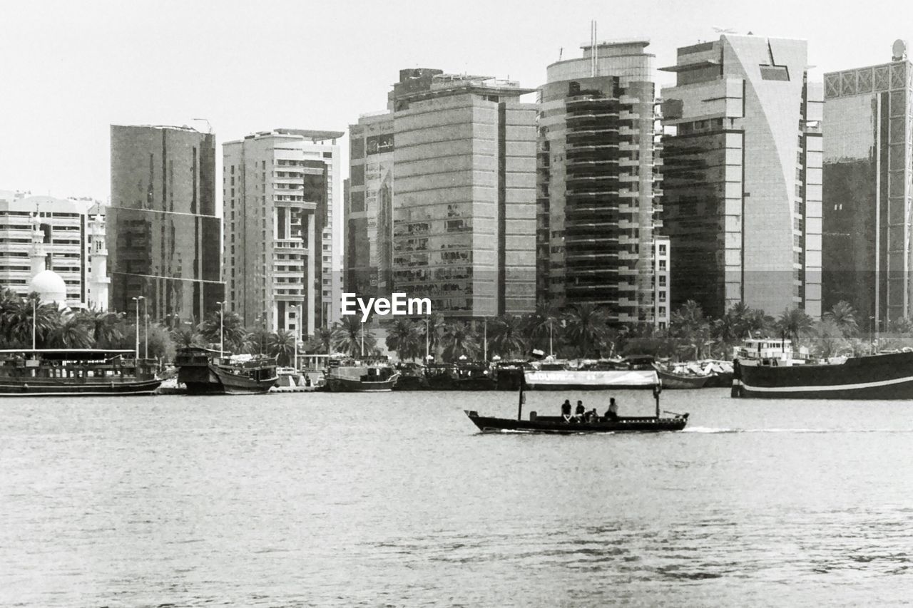 BOAT SAILING ON RIVER BY BUILDINGS IN CITY