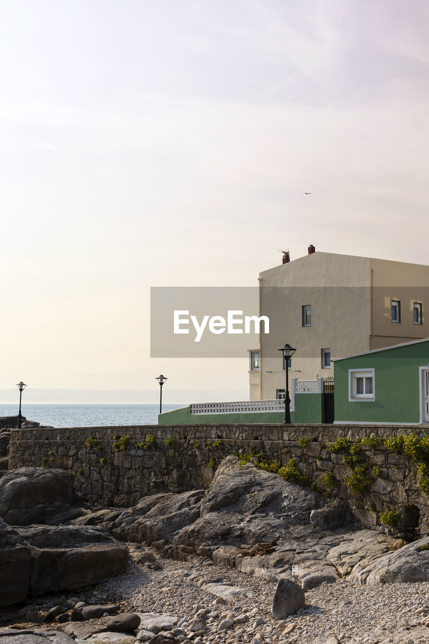 Buildings by sea against sky