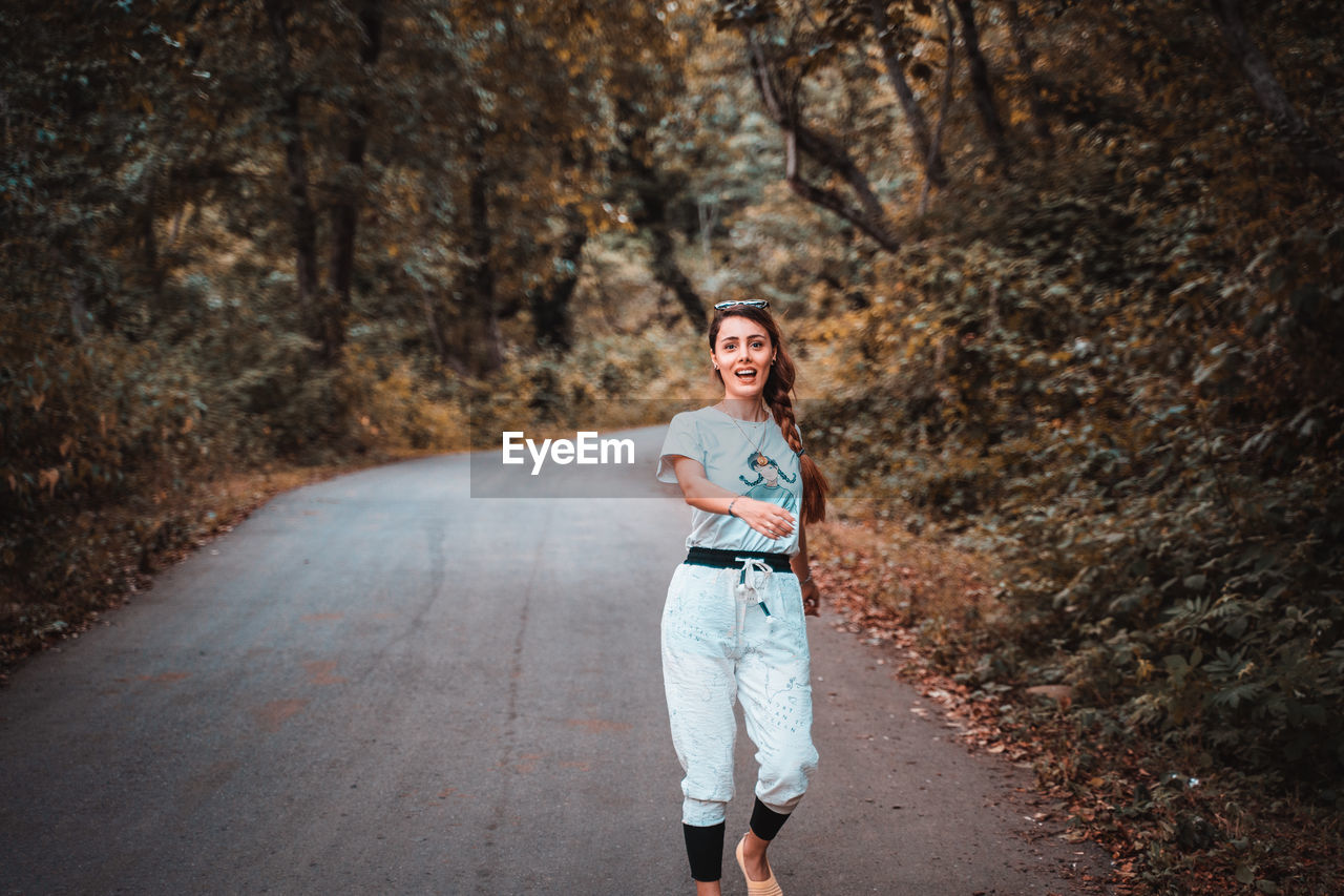 Portrait of young woman standing on road