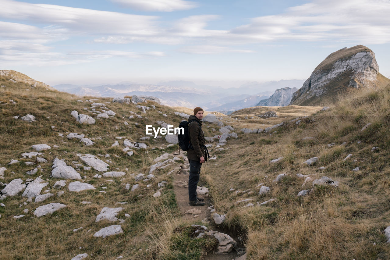 Side view of man standing on land against sky