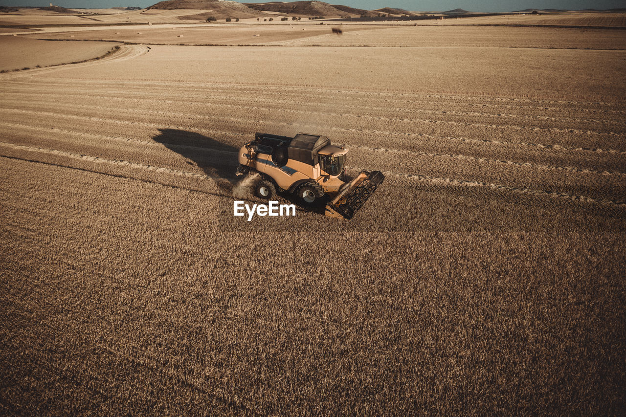 Combine harvester working at sunset from aerial view.