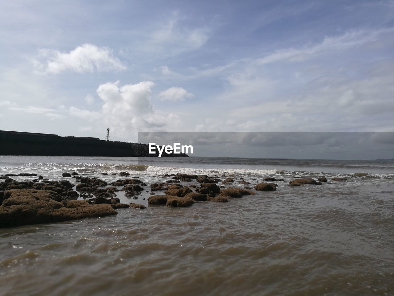 Scenic view of beach against cloudy sky