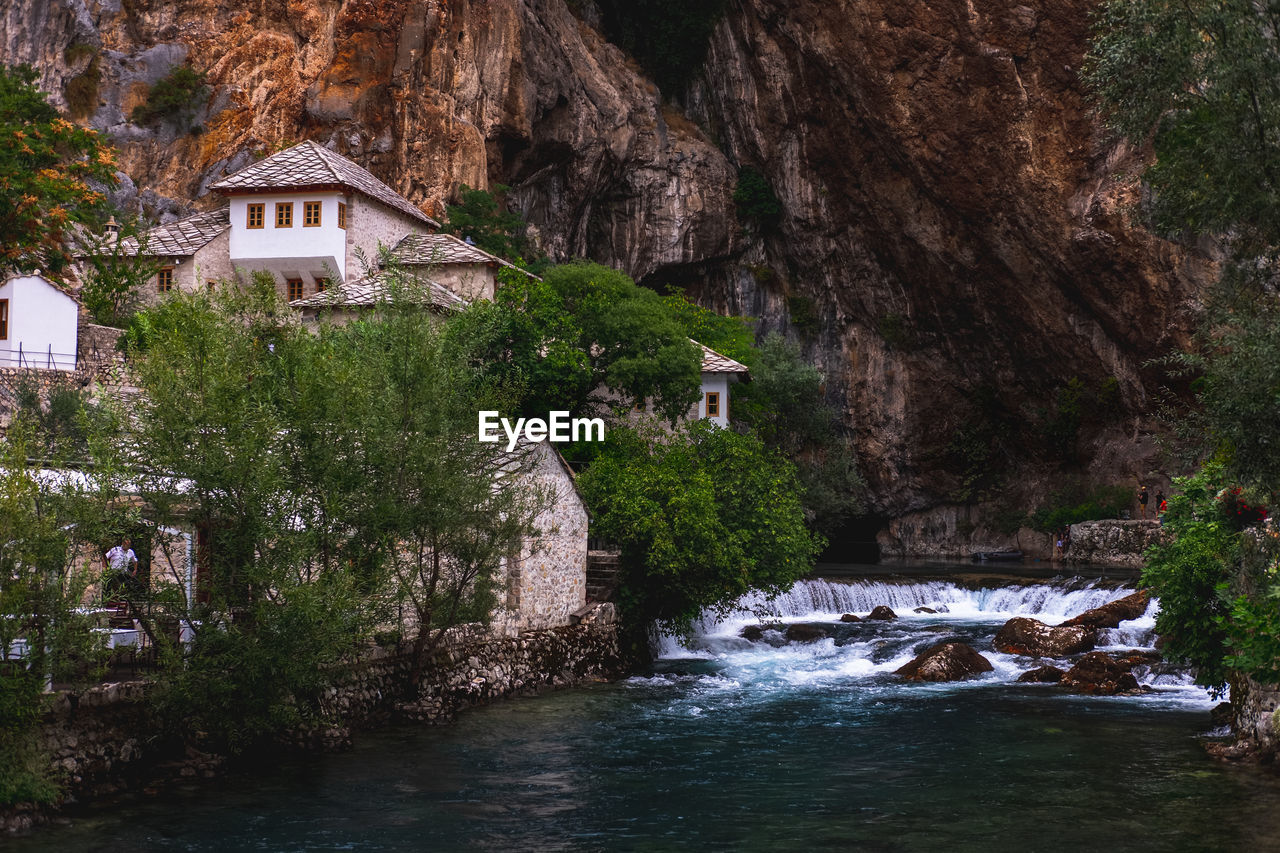 River amidst trees and buildings against mountain