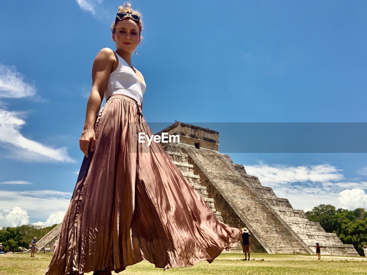 Low angle view of tourists standing by historical building against sky