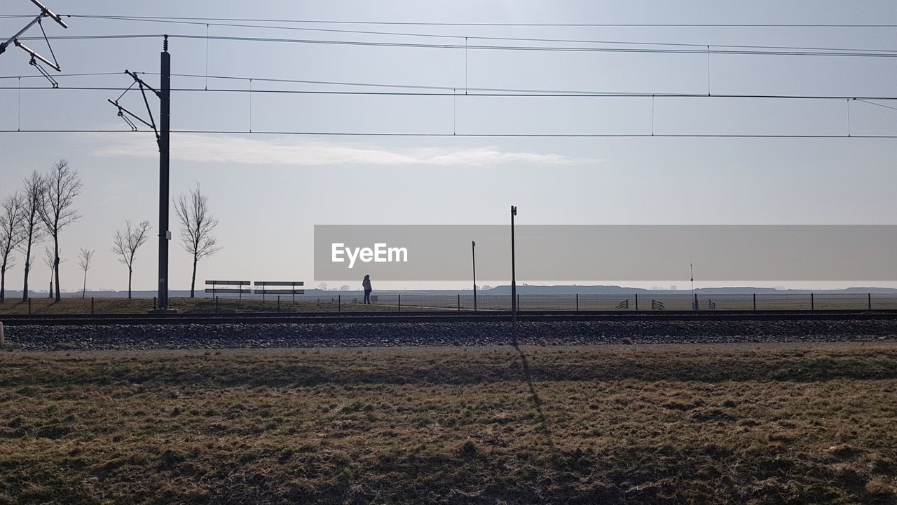 VIEW OF ELECTRICITY PYLON ON FIELD AGAINST SKY