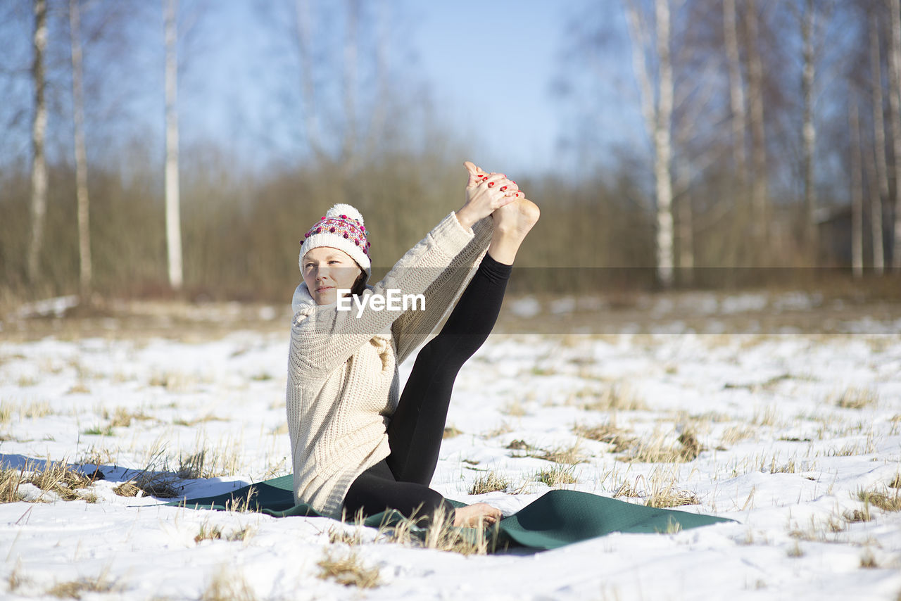 Young attractive woman practicing yoga on snowy field. outdoor sport activity. practice yoga asana. 