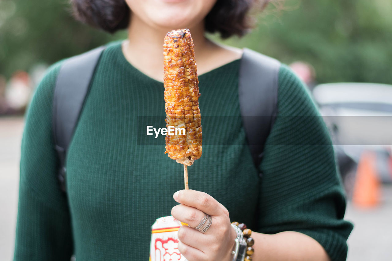 Midsection of woman holding corn 