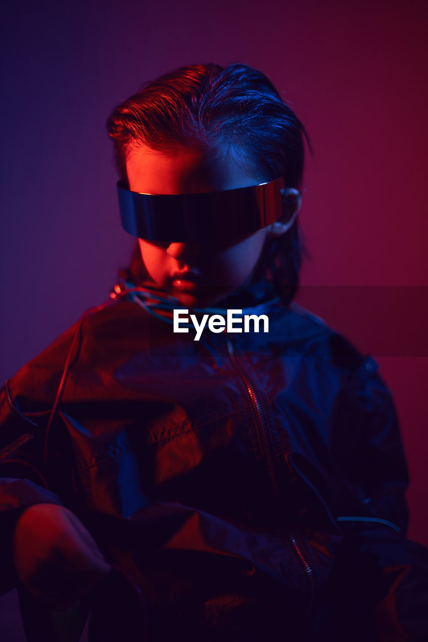 Portrait cyberpunk boy child in vr glasses in blue and red tones. game, virtual reality