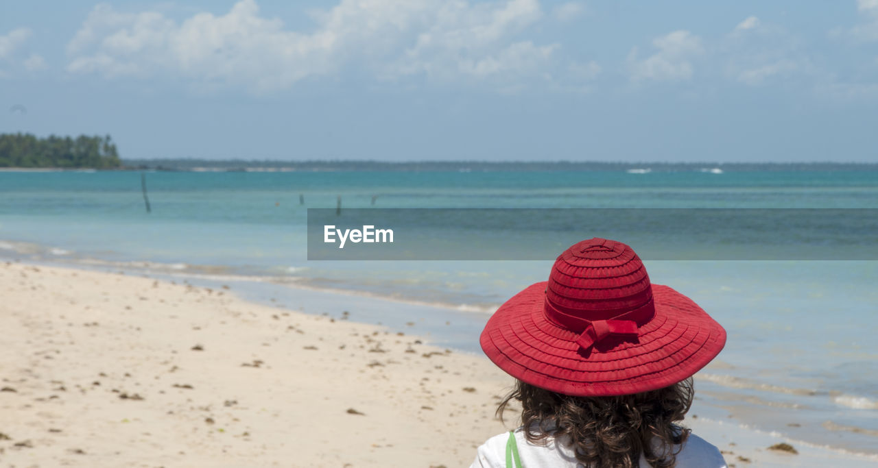 REAR VIEW OF WOMAN LOOKING AT BEACH