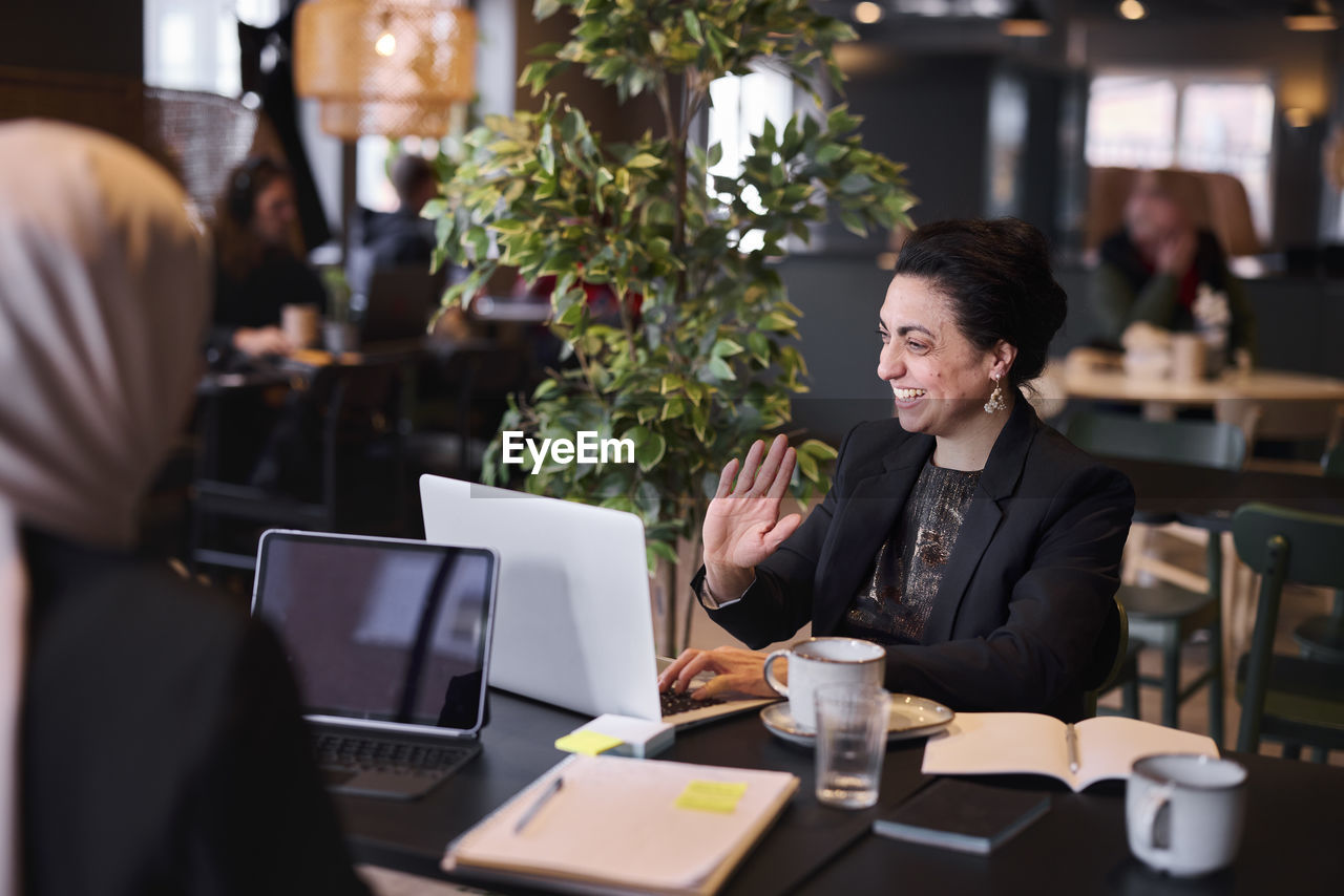 Smiling businesswoman using laptop in cafe