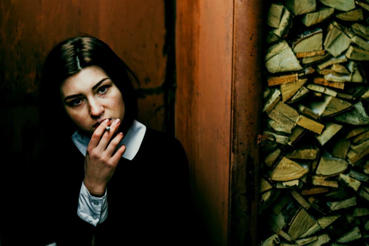 Young woman smoking against rusty wall