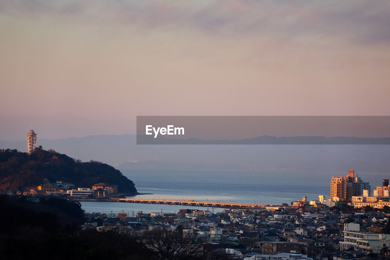 Town by sea against sky during sunset