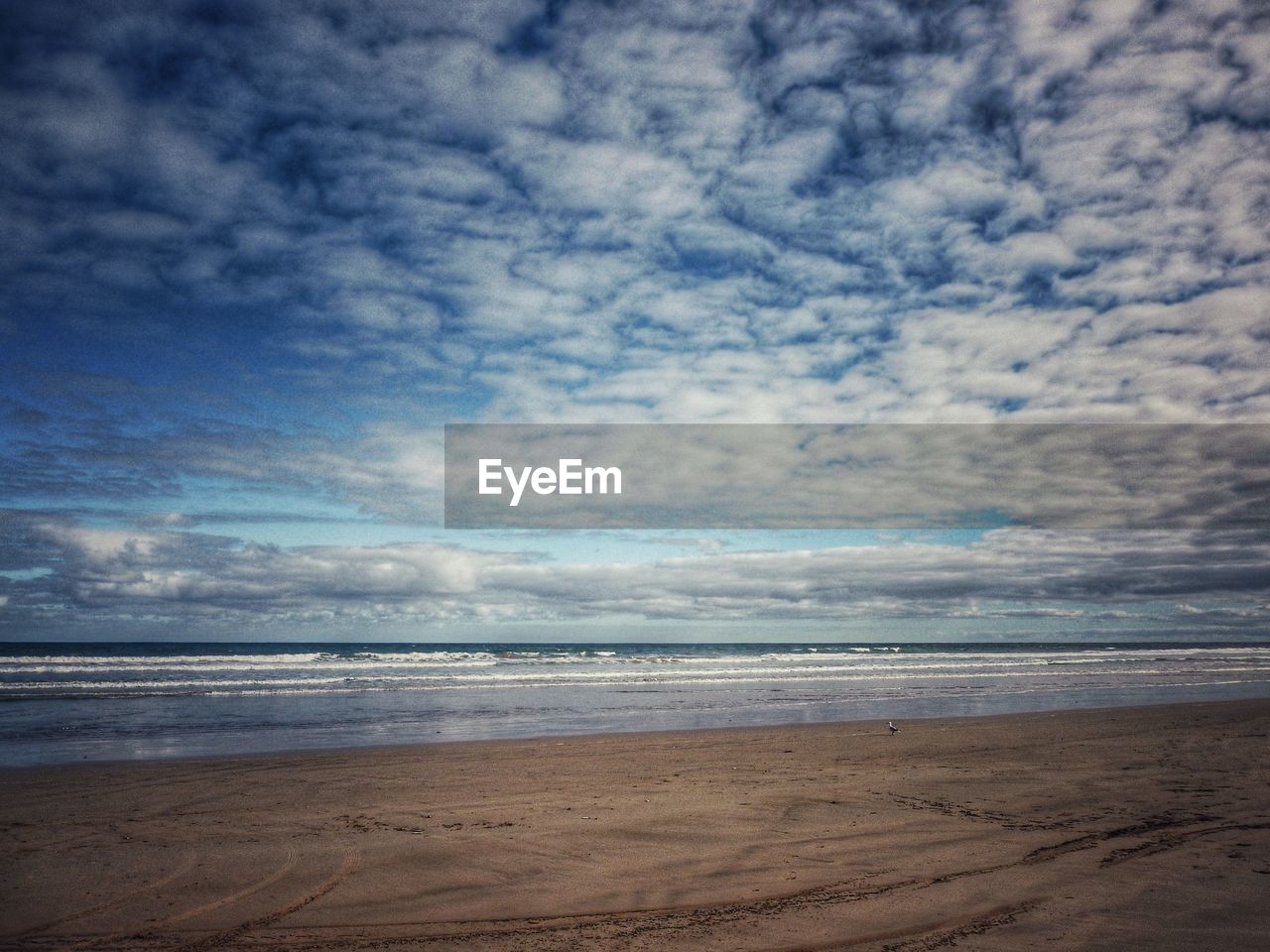 VIEW OF BEACH AGAINST CLOUDY SKY