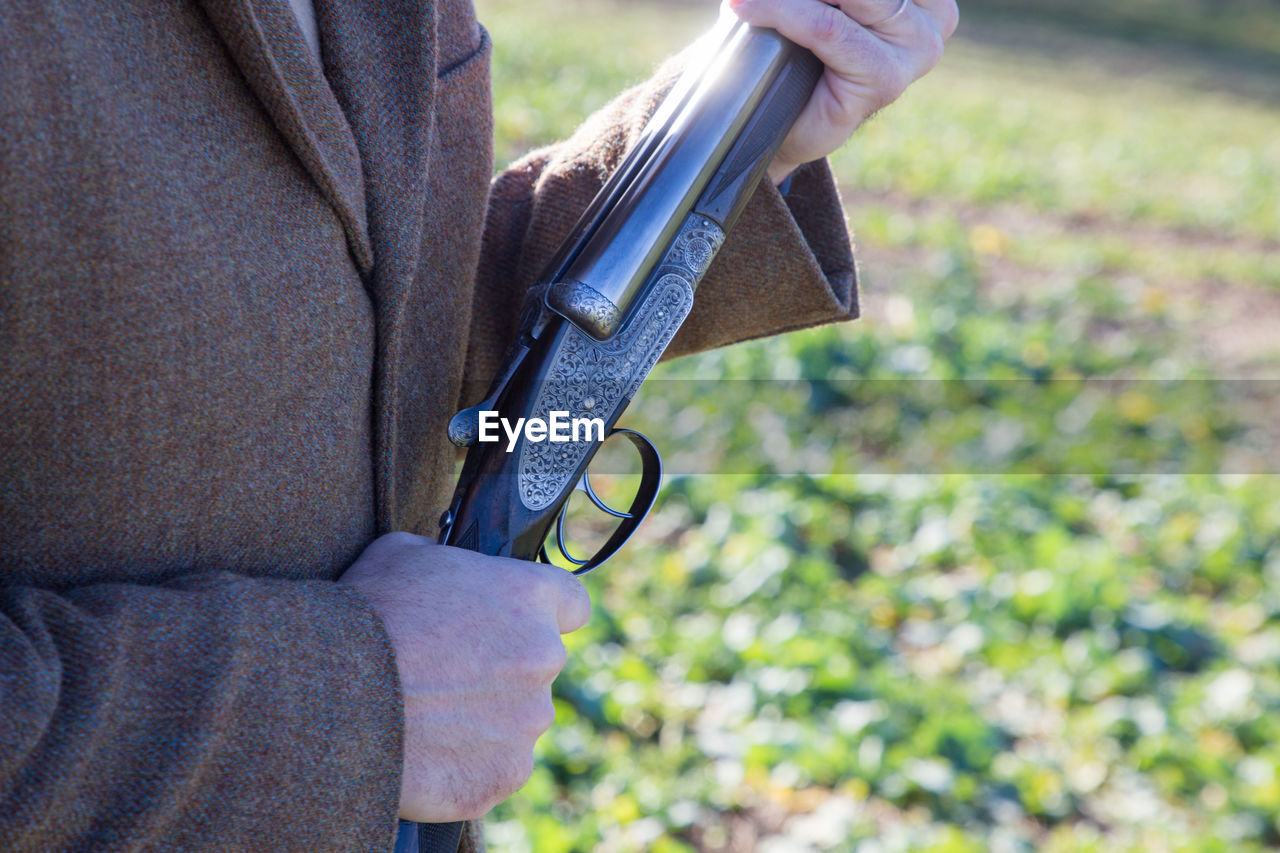 Man holding a shotgun whilst out pheasant shooting.