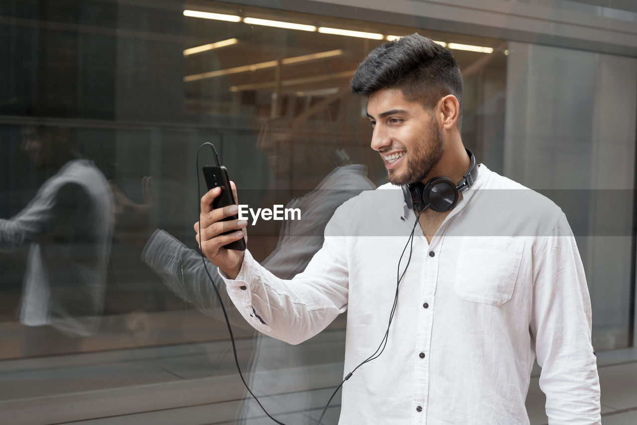 Young man using mobile phone while standing on mirror