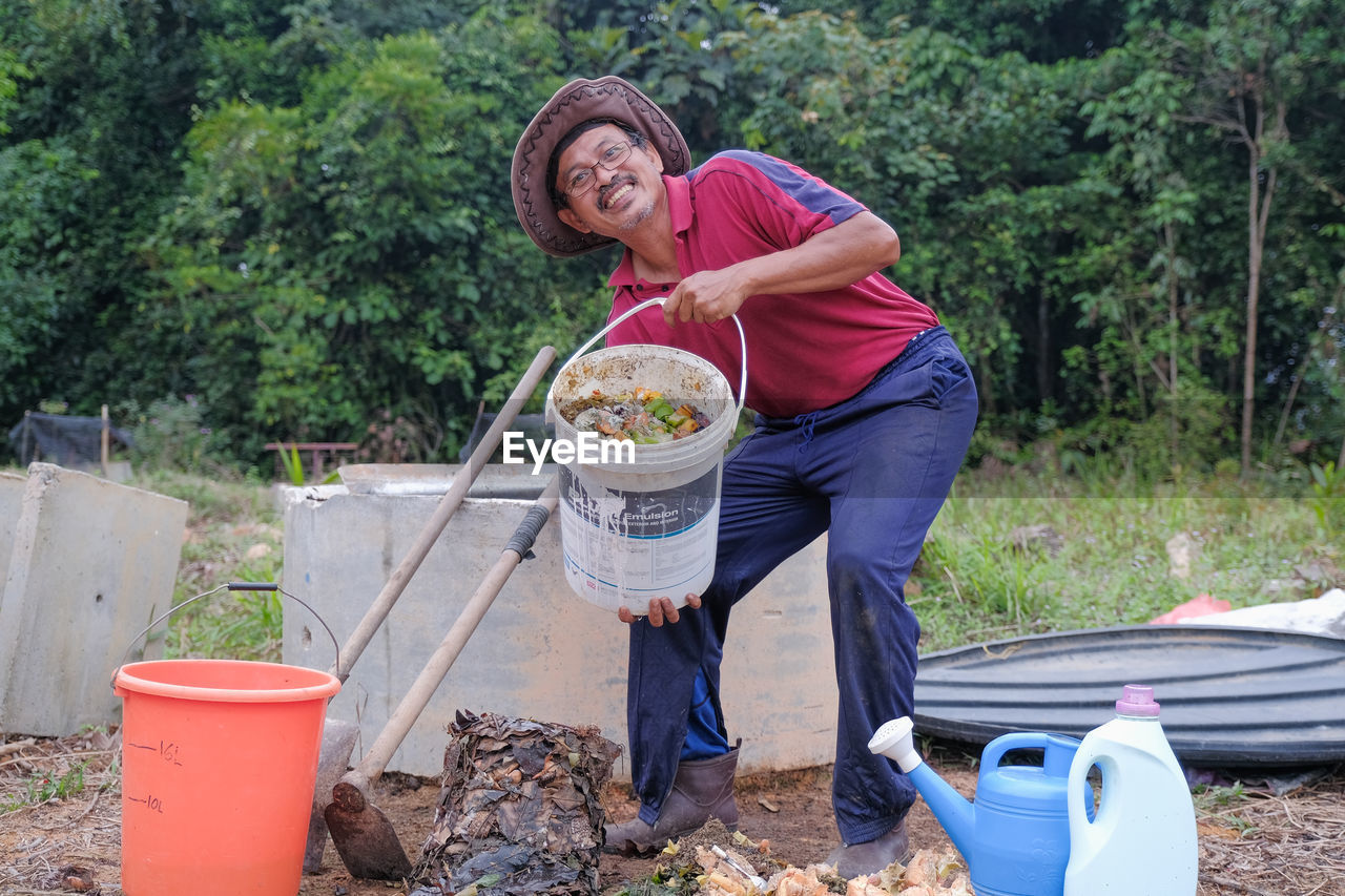 MIDSECTION OF WOMAN STANDING BY PLANTS