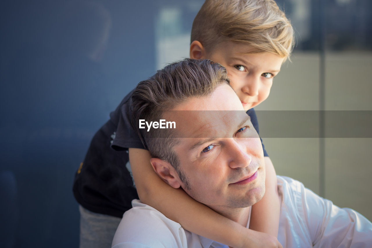 Portrait of father and son against wall