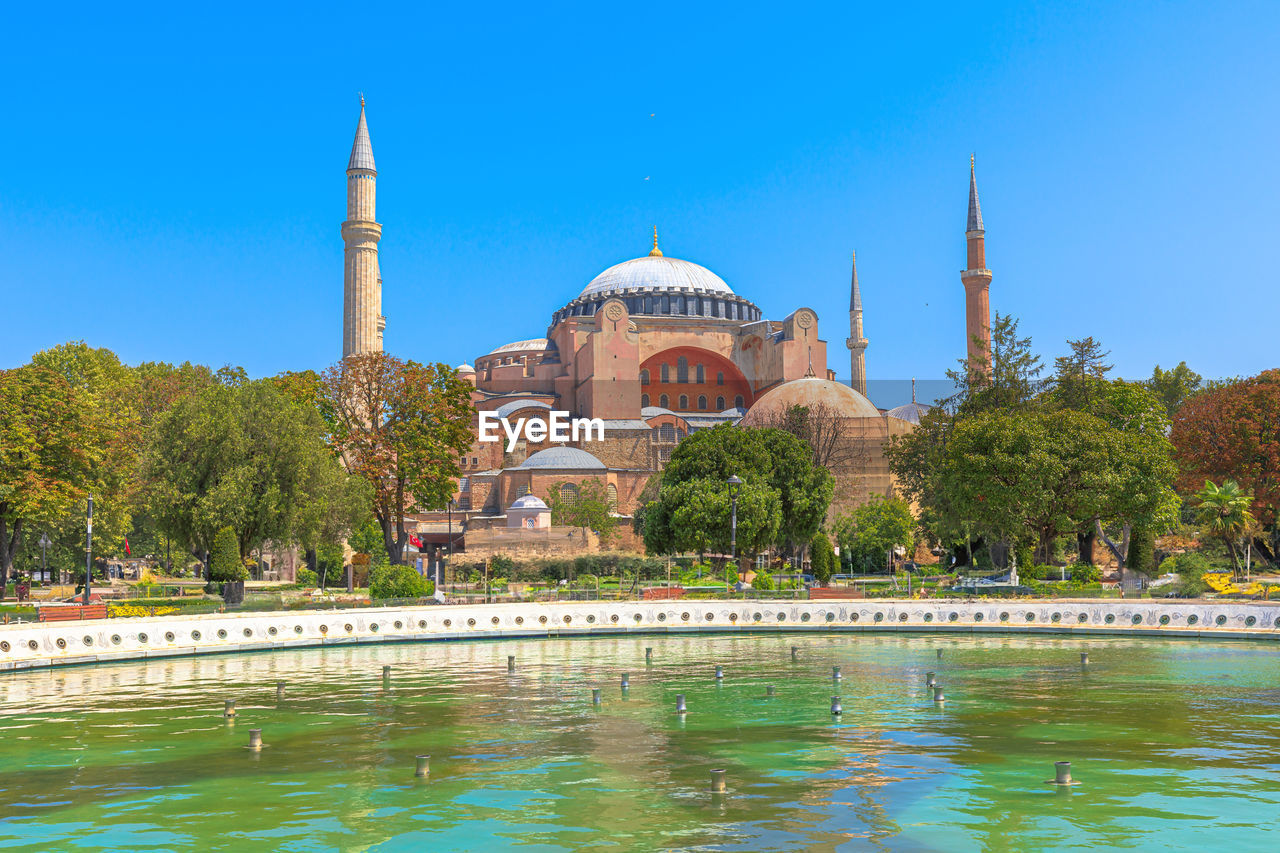 architecture, place of worship, religion, travel destinations, built structure, water, landmark, dome, building exterior, travel, belief, sky, nature, tree, tourism, blue, spirituality, clear sky, plant, building, reflection, history, city, vacation, outdoors, the past, no people, sunny, day