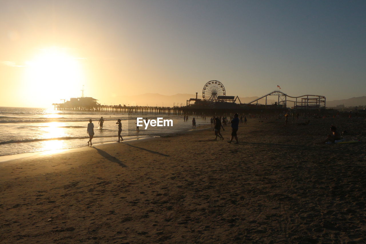 GROUP OF PEOPLE ON BEACH AT SUNSET