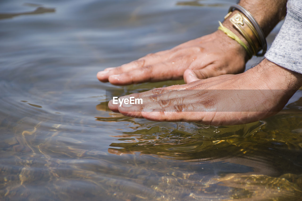 Cropped image of hands over lake